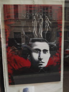 L’opera è un ritratto in bianco e nero di Antonio Gramsci con la sua distintiva e folta capigliatura, su uno sfondo rosso che fa riferimento al comunismo ed evoca la violenza dell’epoca. In cima alla chioma, rispetto a una folla, possiamo riconoscere tre figure in evidenza, una citazione de “Il quarto Stato” (1901) di G. Pellizza da Volpedo che rappresentò pittoricamente la popolazione più svantaggiata, la stessa a cui Antonio Gramsci dedicò un’intera vita con le sue lotte.